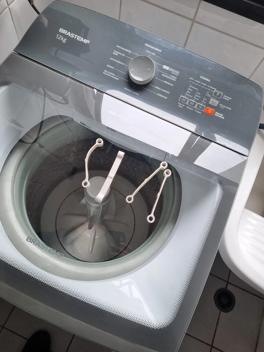 Ferramentas sobre a tampa de uma lavadora Brastemp de 12 kg durante a manutenção