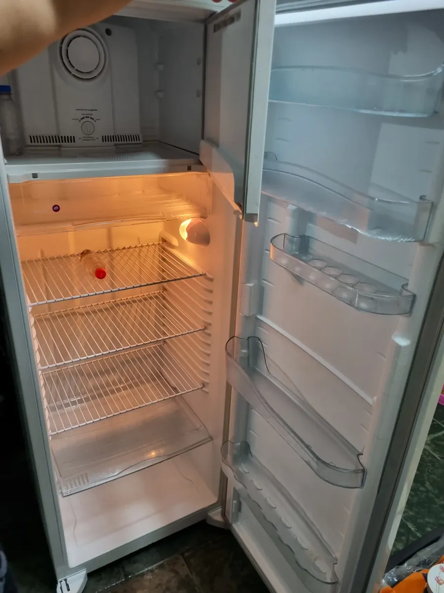 Geladeira branca com freezer superior aberta, voltando a gelar após o conserto