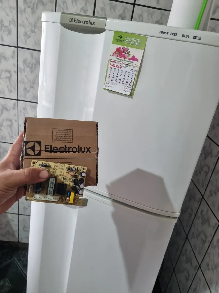 Técnico segurando a placa eletrônica original ao lado de uma Electrolux Frost Free DF34