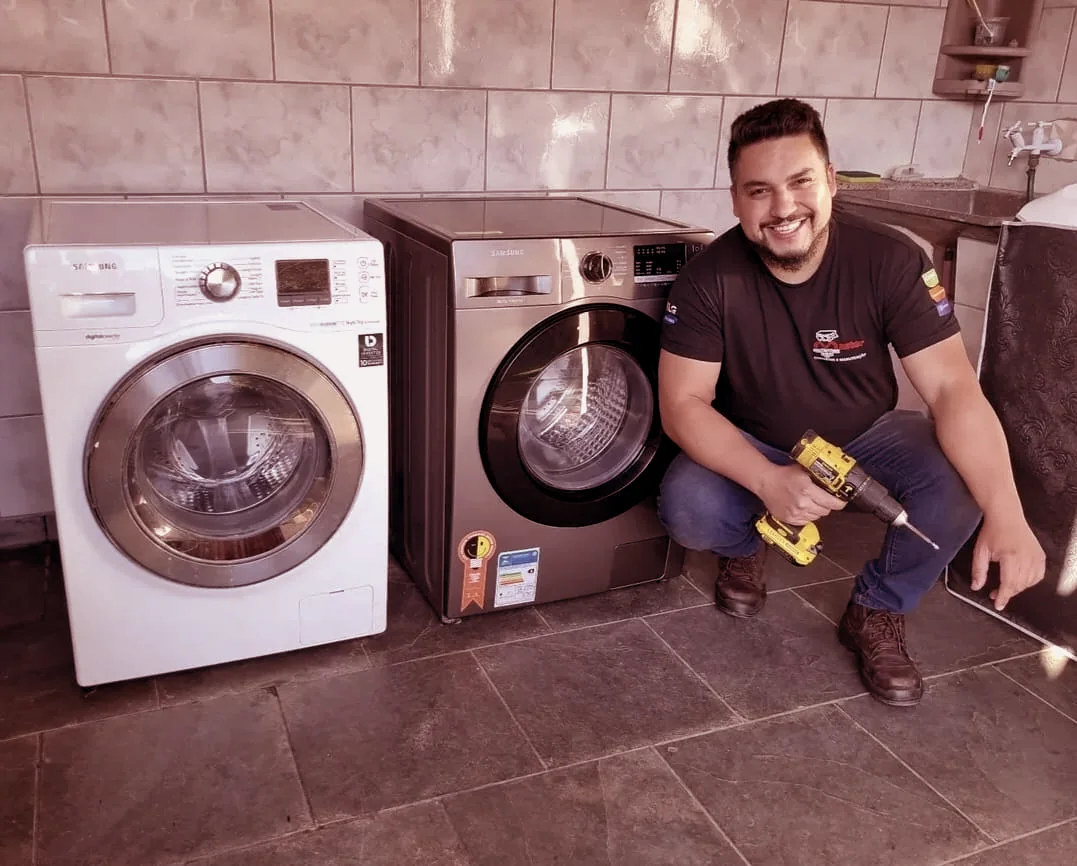 Técnico da Master ao lado de duas máquinas de lavar atendidas na casa do cliente